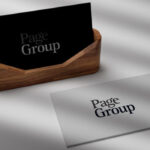 Two Page Group business cards, one black in a wooden holder and one white lying flat, both showing the Page Group logo