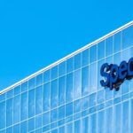 Blue Spectrum logo on the glass facade of a corporate office building under a clear blue sky