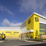 Yellow-clad Big Yellow self-storage building with company logo signs and a reception entrance under a blue sky