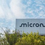 Micron logo on the grey facade of a company building under a blue, partly cloudy sky
