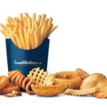 Lamb Weston branded carton of french fries surrounded by onion rings, curly fries, waffle fries, potato wedges and other fried potato products on a white background