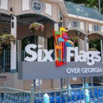 Six Flags Over Georgia entrance sign with the Six Flags logo in front of a flower-decorated pavilion and blue fountain