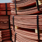 Stacks of strapped copper cathode sheets on wooden pallets stored outdoors