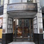 Entrance to a Mulberry store with gold Mulberry lettering and tree logo above glass doors