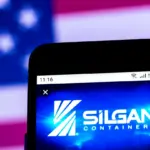 Smartphone screen showing the Silgan Containers logo in front of a blurred American flag