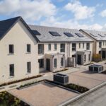 Aerial view of a newly built terraced housing estate with solar panels, paved parking bays and landscaped beds