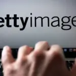 Laptop screen showing the Getty Images logo with a blurred hand moving across the keyboard