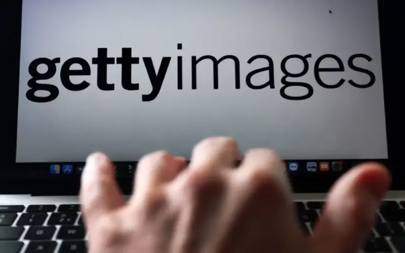 Laptop screen showing the Getty Images logo with a blurred hand moving across the keyboard