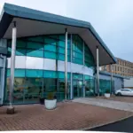 Exterior of a modern glass-fronted office building with a sloping canopy roof and the Fintel logo above the entrance.