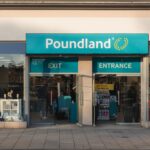Front of a Poundland discount store with its teal Poundland sign above open entrance and exit doors